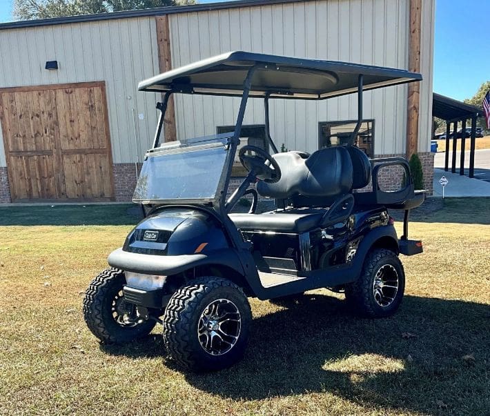 A golf cart with a canopy is parked in the grass.