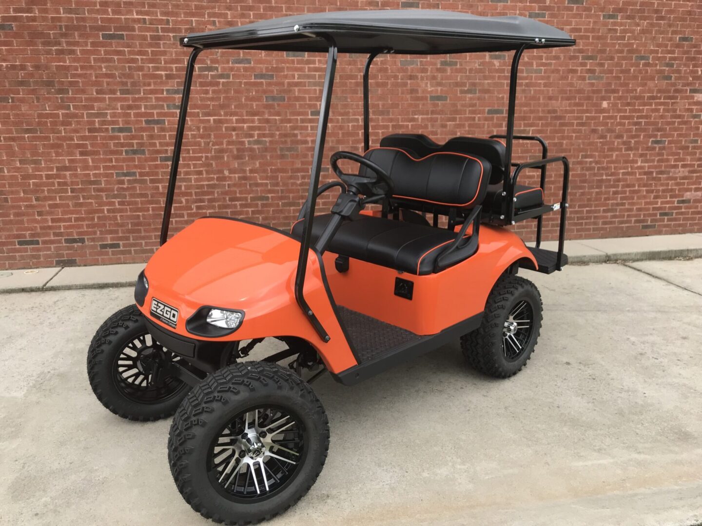 A golf cart with an orange body and black seat.