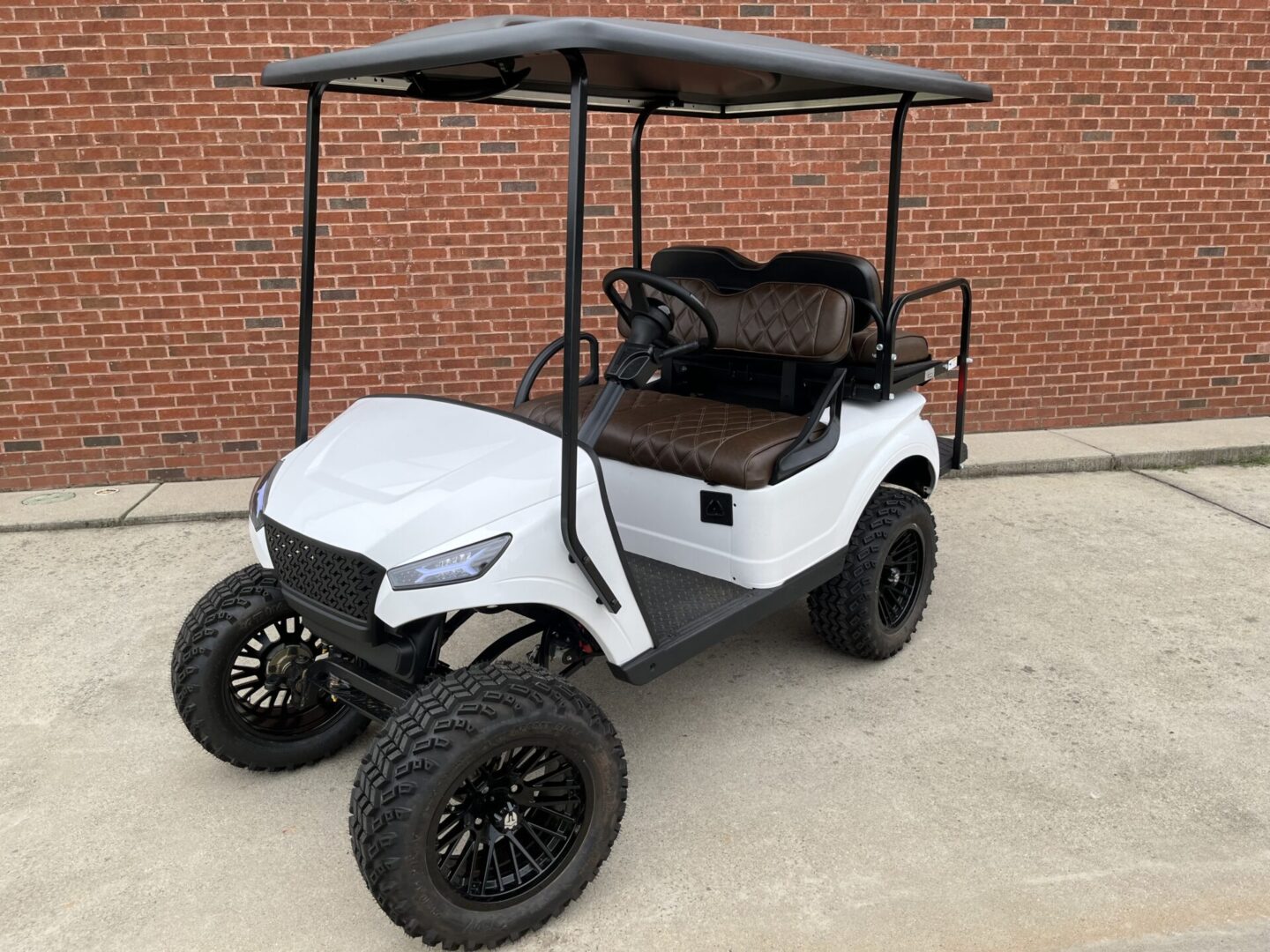 A golf cart with an umbrella over it's top.