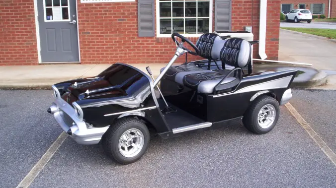 A black golf cart with two seats and a handle.