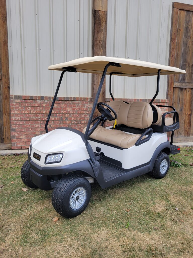 A white golf cart parked on grass near a building.