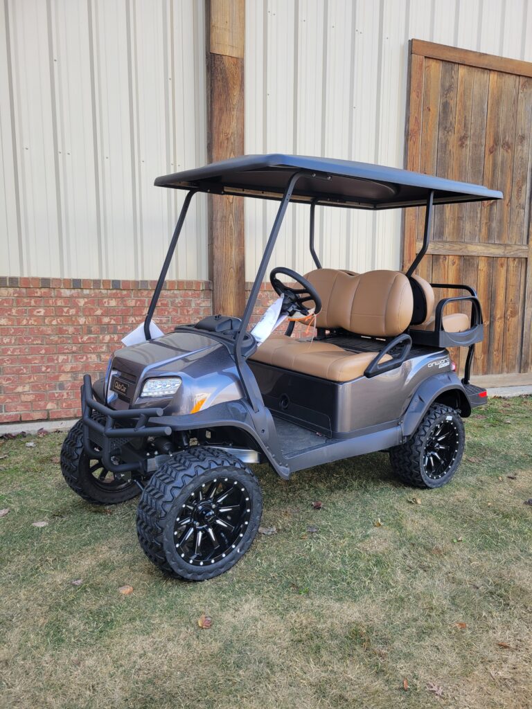 A sleek black golf cart with rugged tires parked on grass.