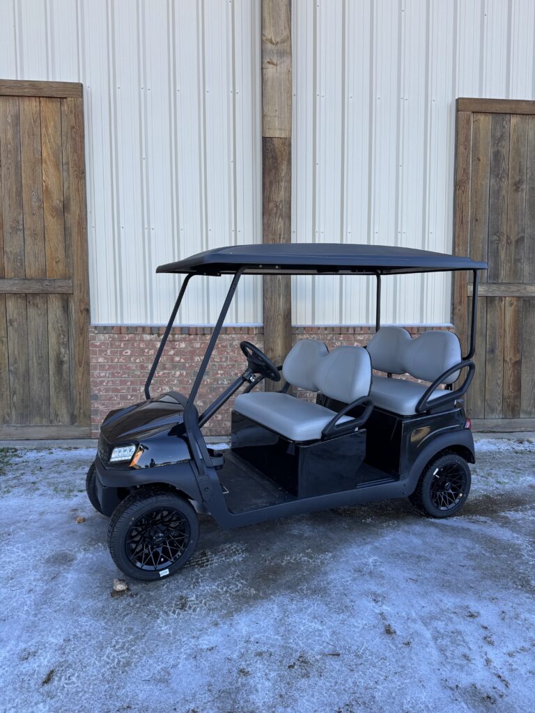 Black golf cart with four seats parked outdoors.