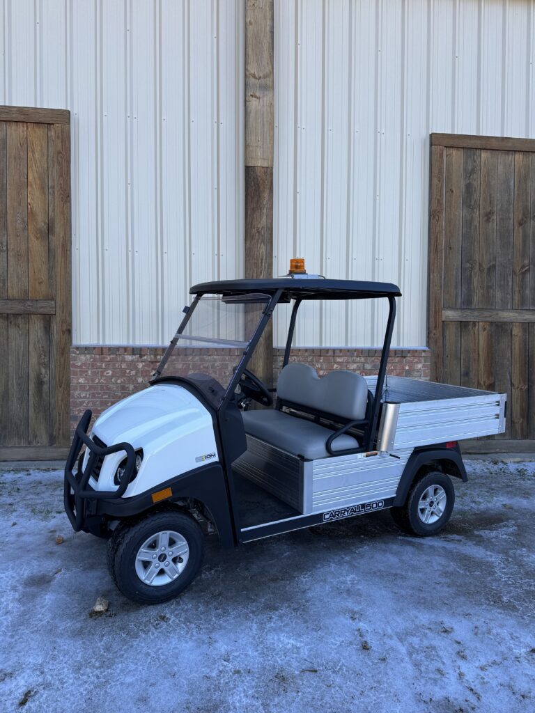 White utility cart parked outside a building with wooden doors.