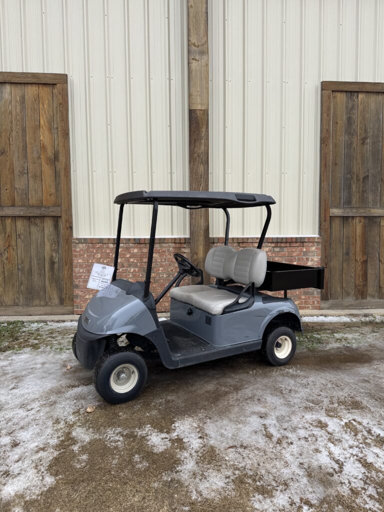 Gray golf cart parked outside near wooden doors.