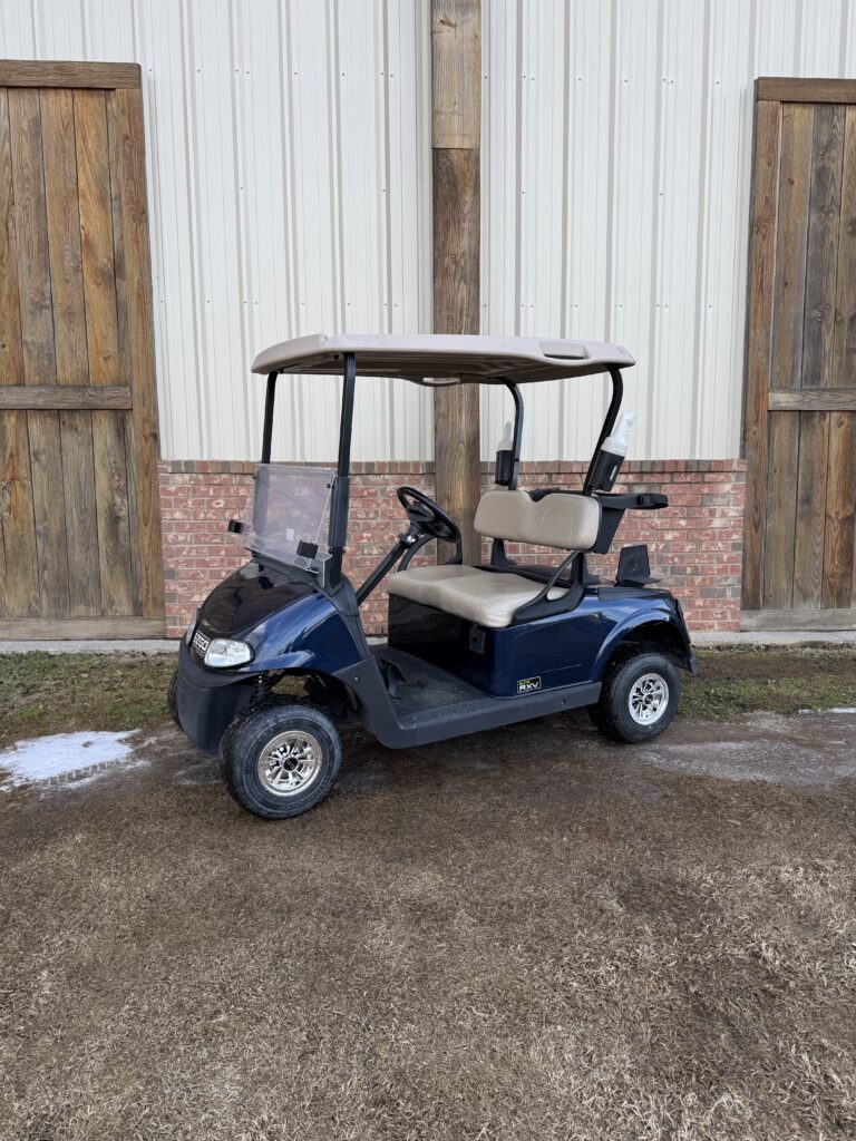 A blue golf cart parked outdoors in front of a wooden and metal building.