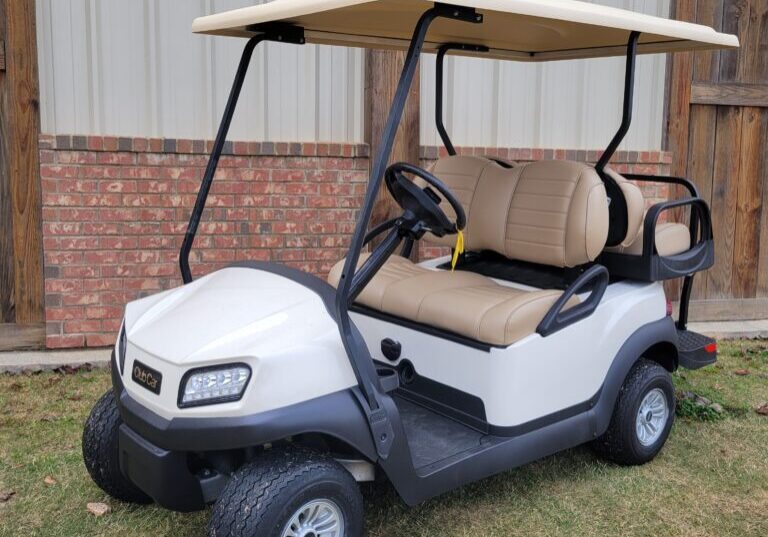 A white golf cart parked on grass near a building.