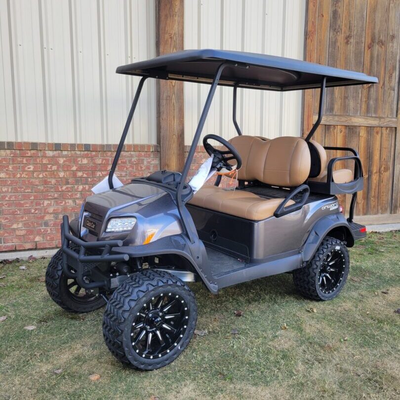 A sleek black golf cart with rugged tires parked on grass.