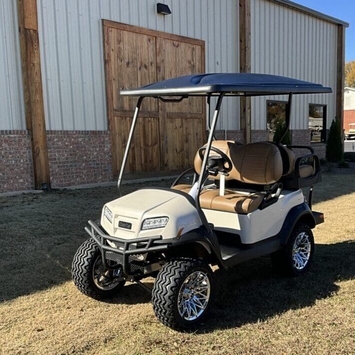 A golf cart with a canopy is parked in the grass.