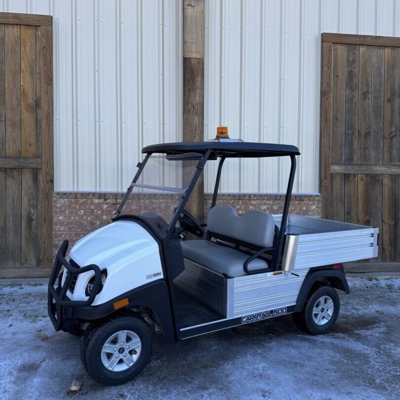 White utility cart parked outside a building with wooden doors.