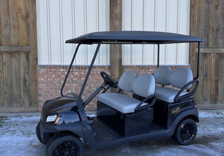 Black golf cart with four seats parked outdoors.