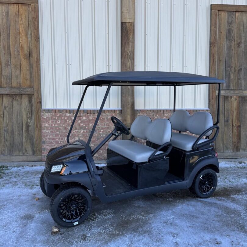 Black golf cart with four seats parked outdoors.