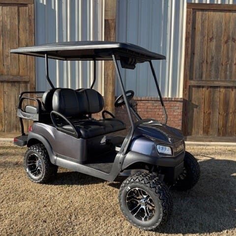 A golf cart is parked in the dirt.