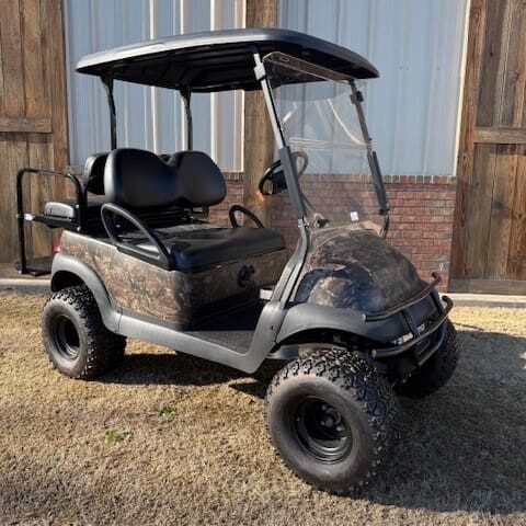 A golf cart is parked in the dirt.
